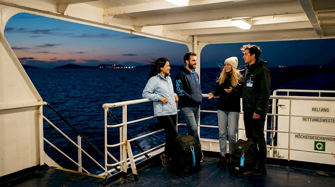 Reisende genießen die nächtliche Überfahrt auf dem Deck einer griechischen Fähre.
