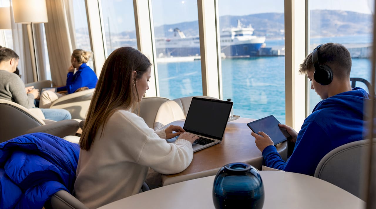 Passeggeri che lavorano al computer portatile o navigano con il tablet nella sala relax del traghetto