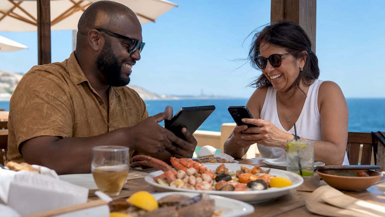 Dos amigos conectados al Wi-Fi mientras disfrutan en un restaurante turístico.